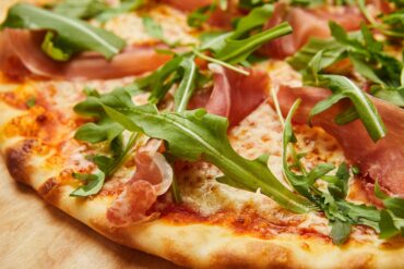 Pizza mit Parmaschinken und Rucola - Parmesan Flocken